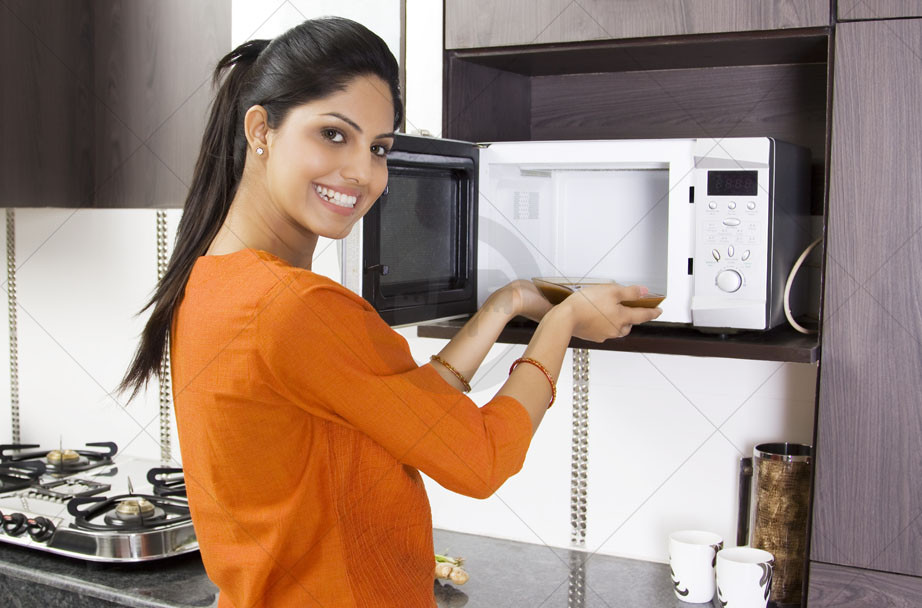 Alt: Lò vi sóng đang hoạt động, bên trong có thức ăn đang được hâm nóng, minh họa cho việc sử dụng lò vi sóng tiết kiệm điện